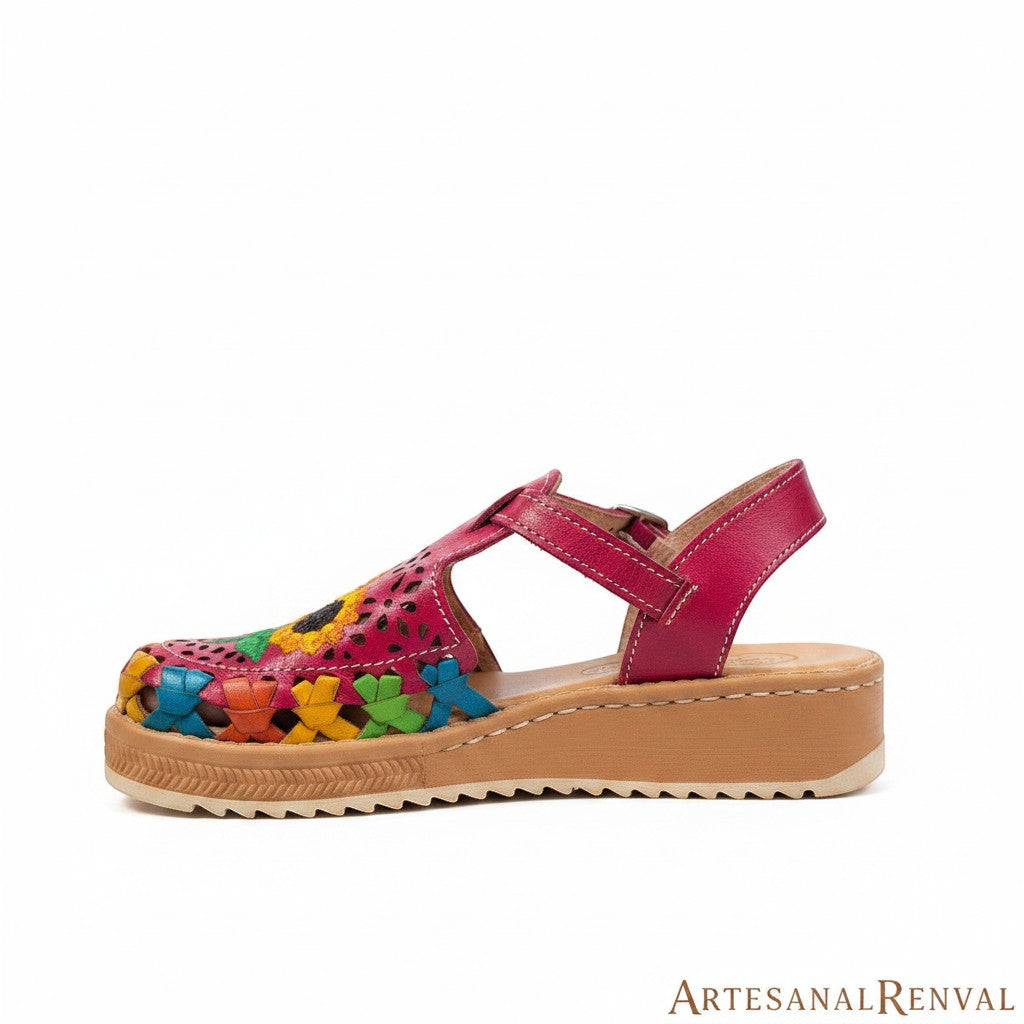 ARTESANALRENVAL fuchsia leather huarache sandal with woven multicolor floral detail and adjustable strap.