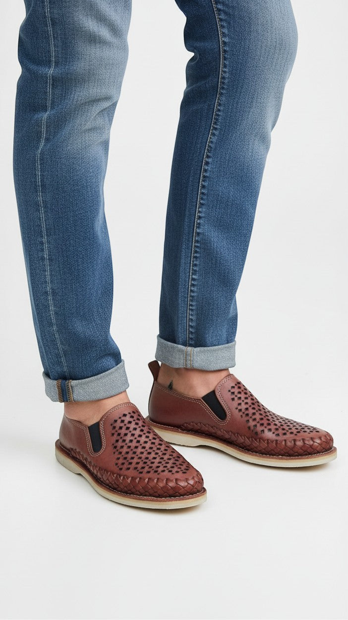 Mocasines ARTESANALRENVAL de piel marrón con diseño calado, trenzado perimetral y elásticos laterales con jeans.