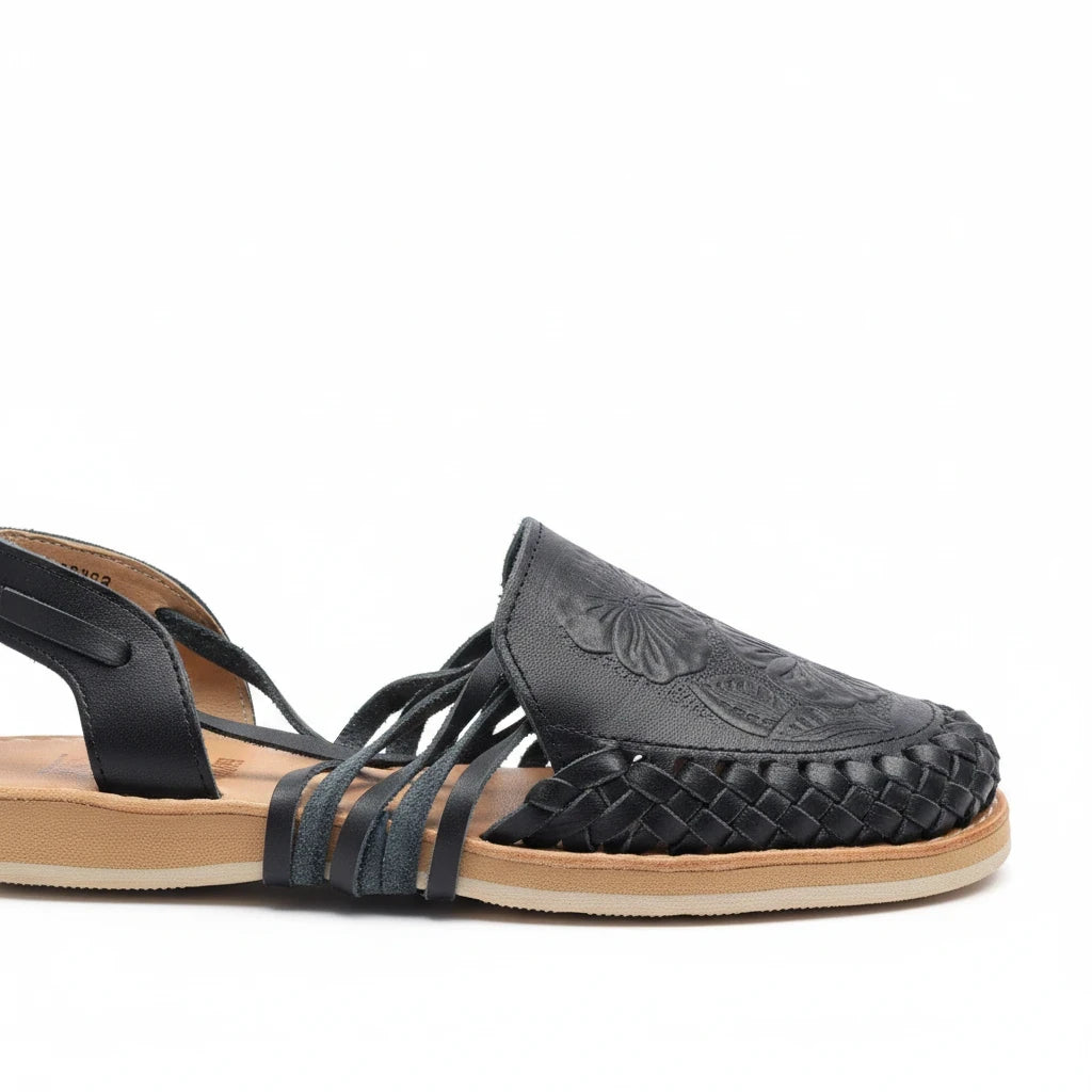ARTESANALRENVAL black leather huarache sandal with hand-tooled tulip design and woven details on a flat sole
