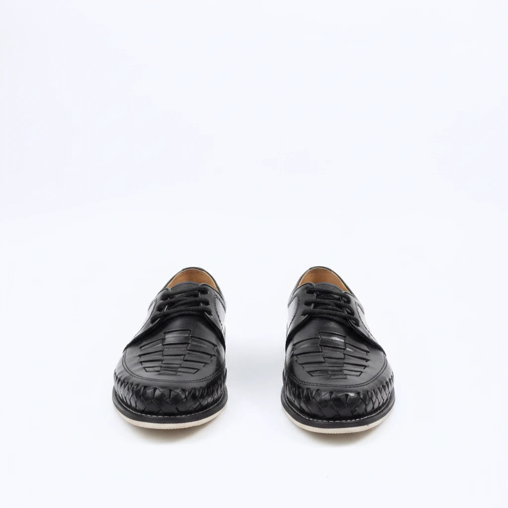 ARTESANALRENVAL black leather huarache shoes with woven detailing and lace-up closure on a white background
