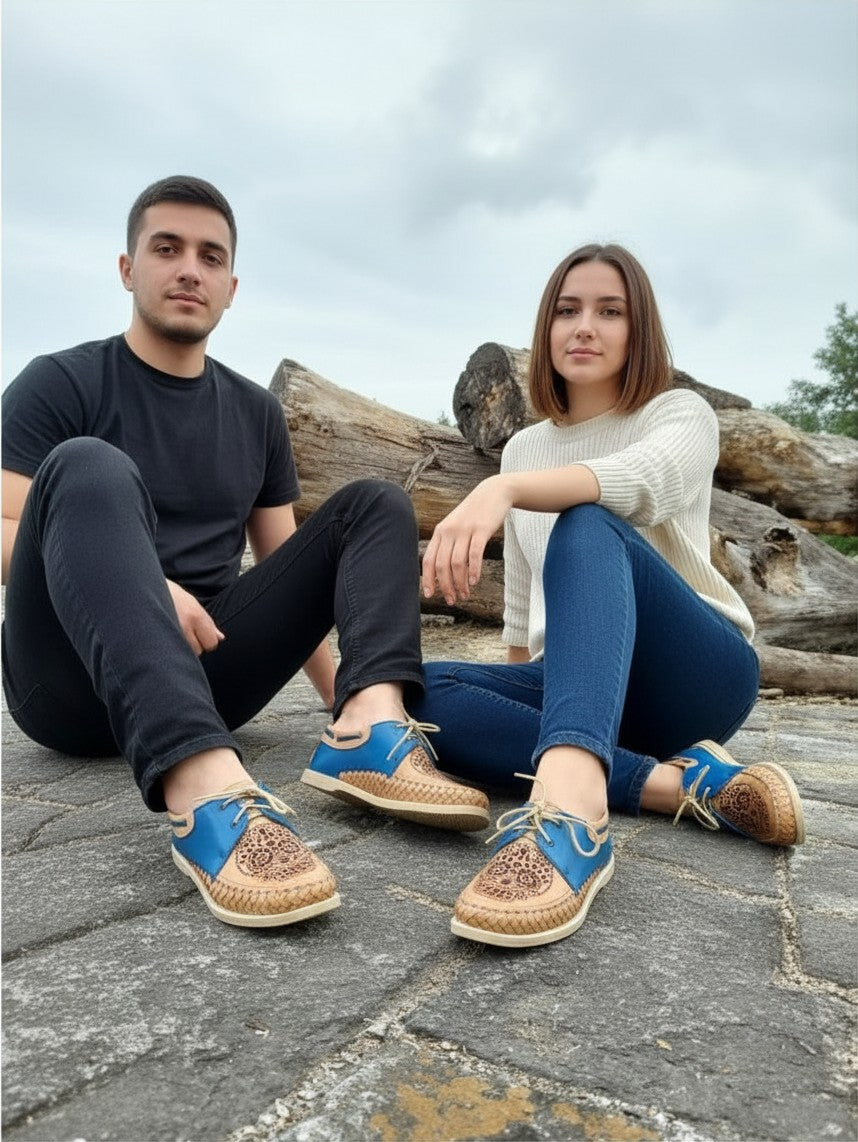 ARTESANALRENVAL handmade blue and tan leather Catrina moccasins worn by a man and woman sitting on stone outdoors.