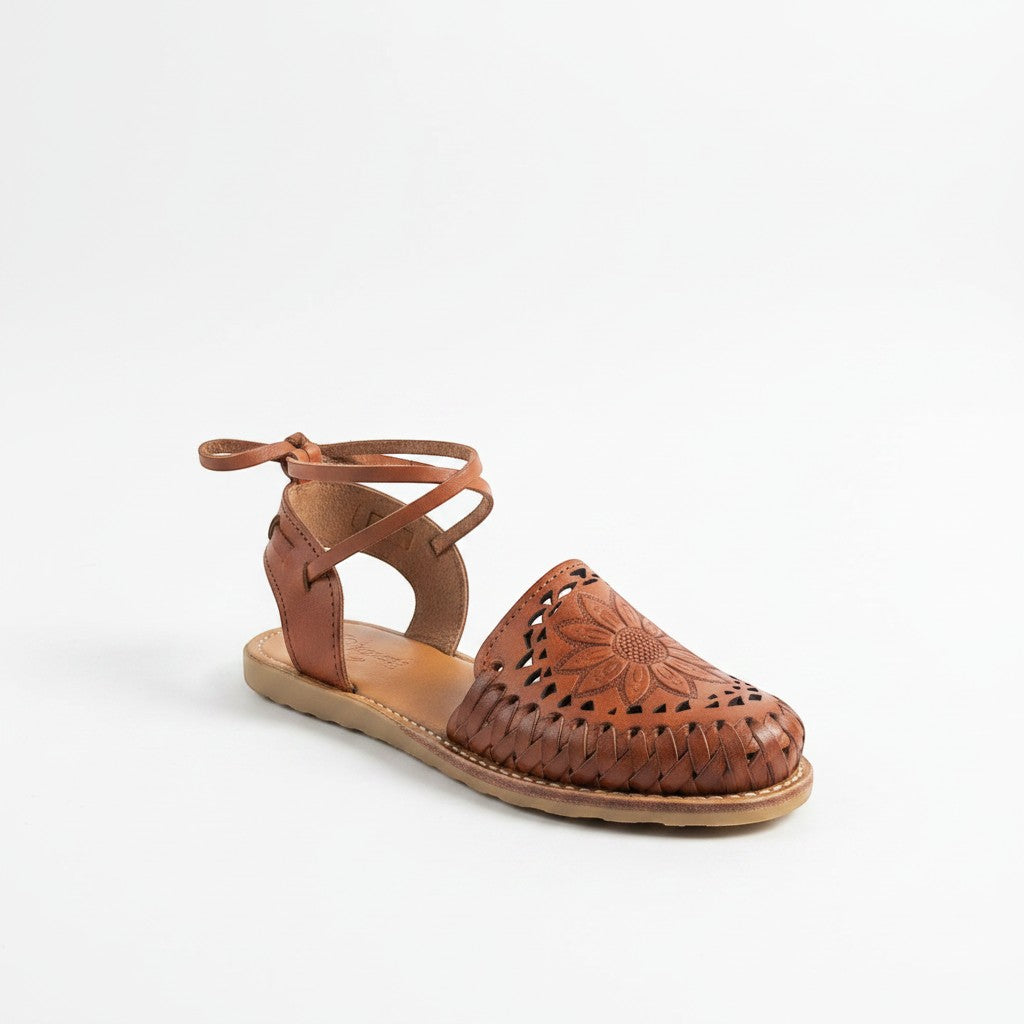 ARTESANALRENVAL brown leather huarache sandal with floral engraving and ankle ties.