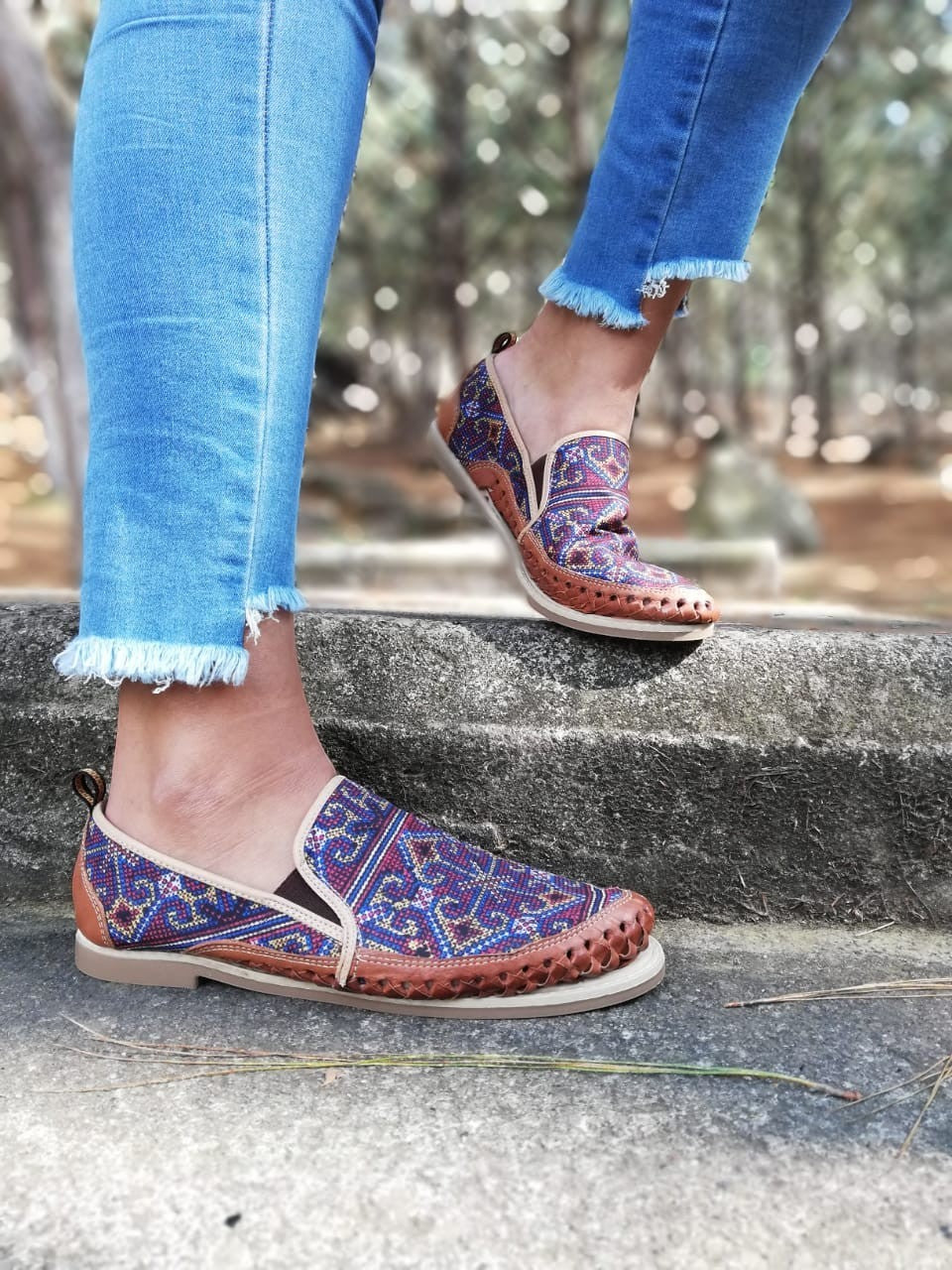 ARTESANALRENVAL women's slip-on shoes with vibrant geometric textile upper in blue, red, and orange, brown leather trim, and low profile sole.