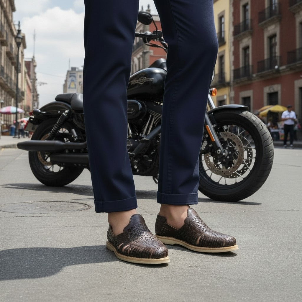 Huaraches ARTESANALRENVAL de piel café con tejido artesanal, usados con pantalones azul marino y una motocicleta.