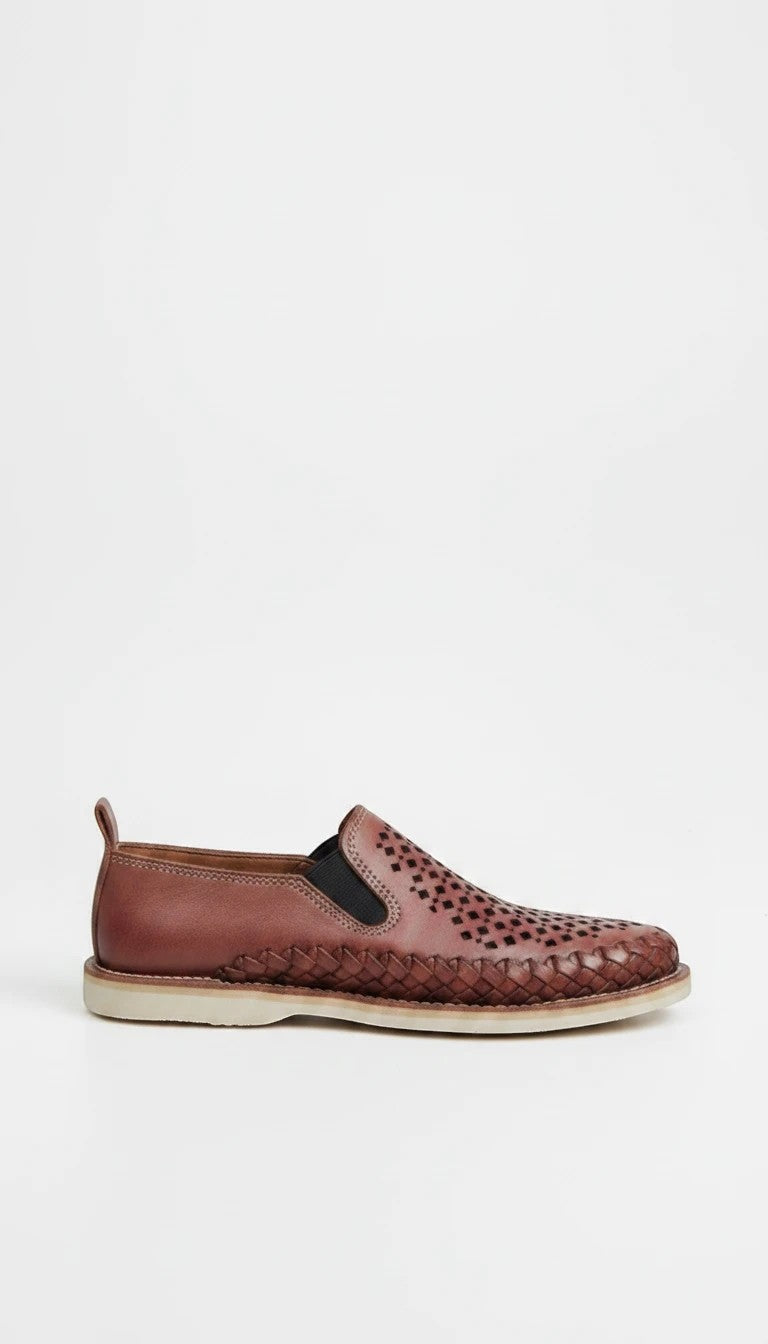 Mocasín ARTESANALRENVAL de piel marrón con diseño calado, trenzado perimetral, paneles elásticos y suela de goma.