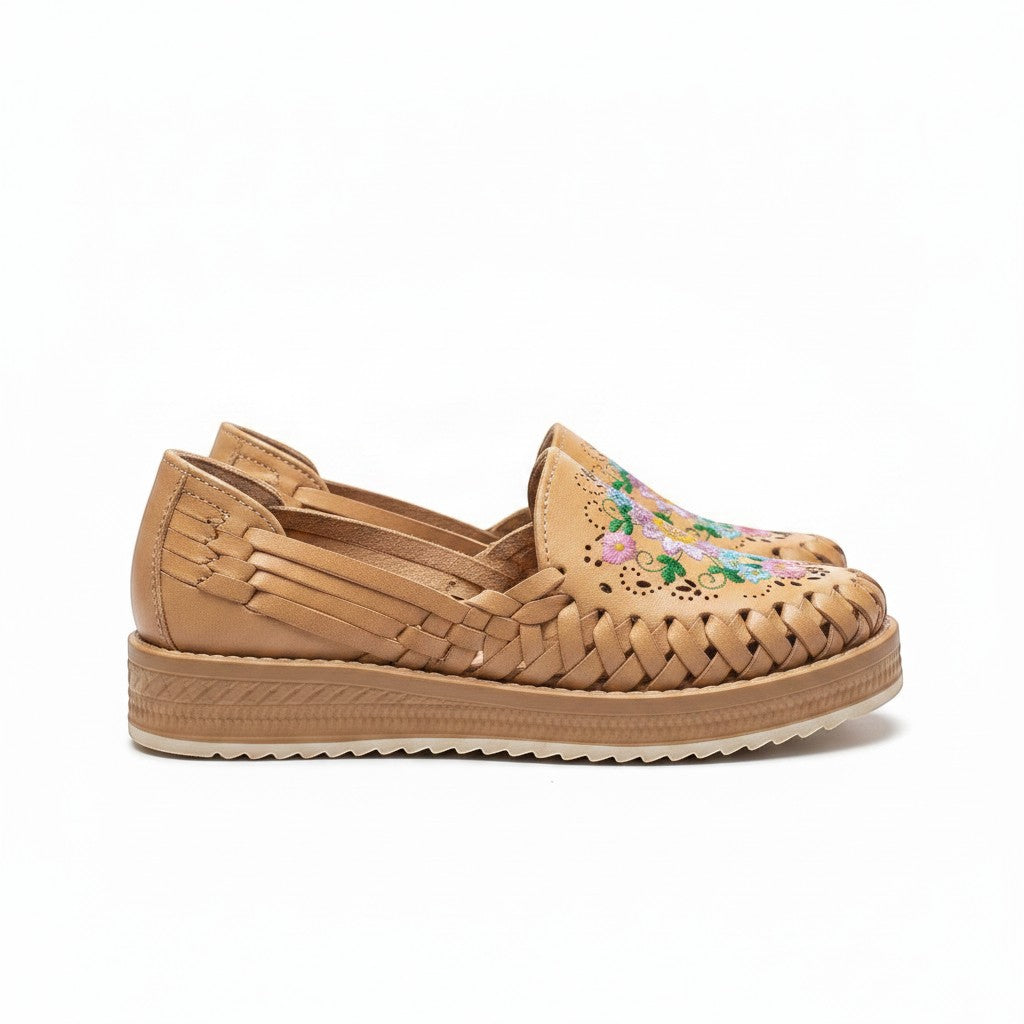 ARTESANALRENVAL tan huarache moccasin with woven leather and multicolor floral embroidery. Closed toe, open sides, and light sole.