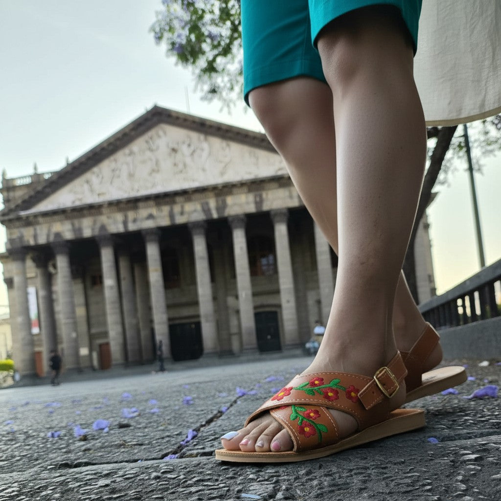 ARTESANALRENVAL tan leather huarache sandals with red floral embroidery and gold buckle.