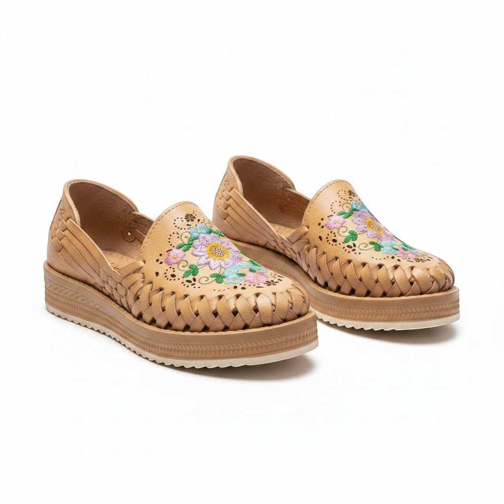 ARTESANALRENVAL tan huarache moccasin shoes with woven sides and multicolor floral embroidery on the vamp.