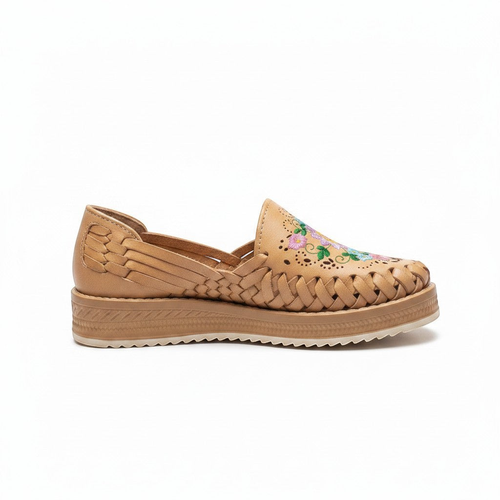 ARTESANALRENVAL tan huarache moccasin with woven leather and multicolor floral embroidery. Features a closed toe, perforated details, and a light, non-slip sole.