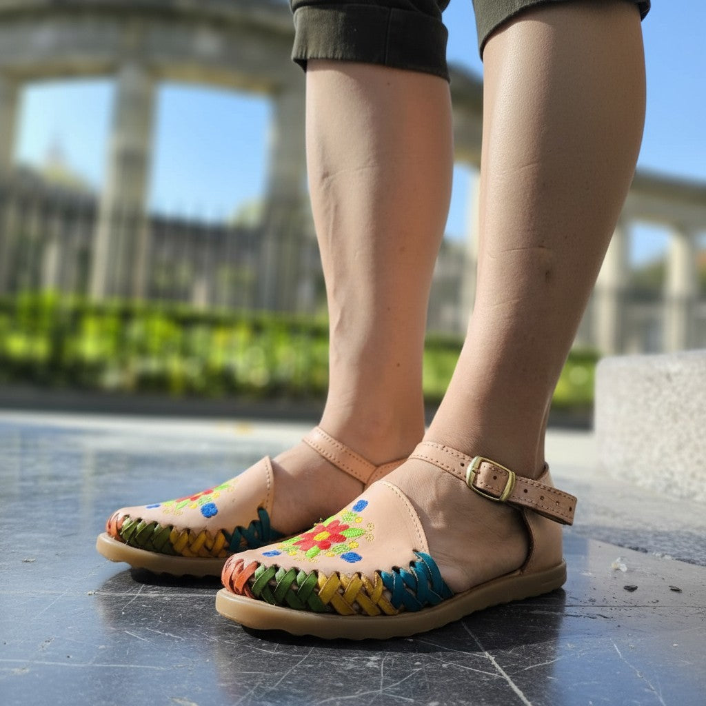 ARTESANALRENVAL tan leather huaraches with colorful floral embroidery and woven straps. Adjustable ankle strap with buckle.